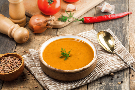 Lentil soup in a rustic bowl on a cotton canvas tablecloth. Healthy vegetarian food on an old wooden table. Top view.の写真素材
