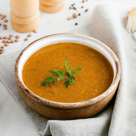Bowl of delicious lentil soup with bread and lemon slice on a white wooden table. Traditional healthy vegetarian food. Top view.の写真素材