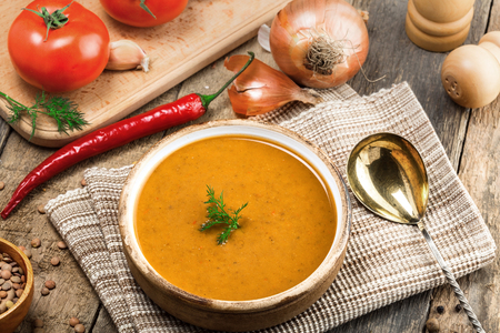 Delicious soup made of lentils in a rustic clay bowl served on a canvas tablecloth. Healthy vegetarian meal on a wooden table. Top view.の写真素材