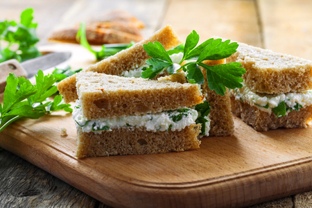 Sandwiches made of rye bread, cream cheese, green onion and fresh parsley on a rustic table. Delicious healthy appetizers. Close-up shot.の写真素材