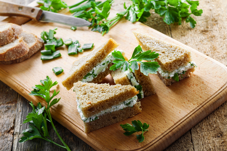 Cream cheese sandwiches with fresh parsley and green onion on a rustic table. Healthy homemade appetizer. Close-up shot.の写真素材