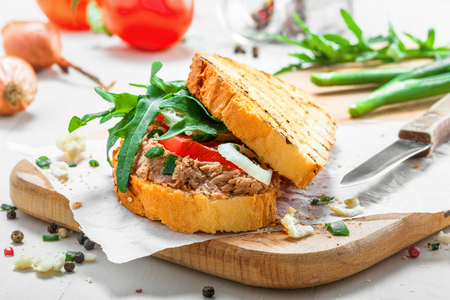 Classic tuna salad sandwich with tomato, onion and arugula on a white table. Delicious healthy meal made of fish, vegetables and toasts.の写真素材