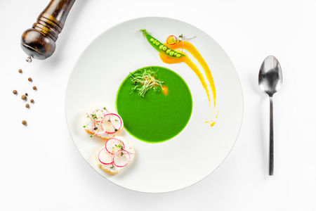 Pea cream soup in a rim soup plate. Classic European food isolated on white background.の写真素材