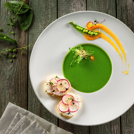 Healthy pea cream soup in a rim soup plate. Delicious European cuisine meal.の写真素材