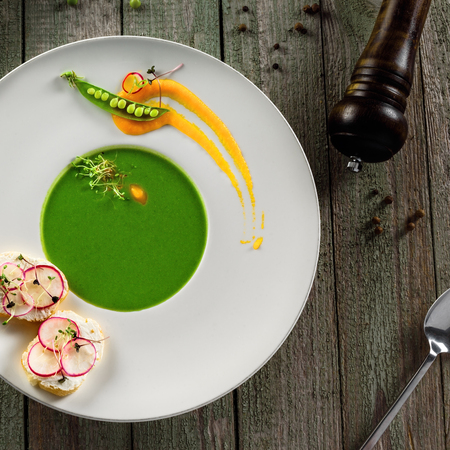 Delicious pea cream soup in a rim soup plate. Healthy traditional European cuisine food on a table.の写真素材