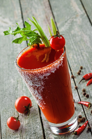 Glass of classic bloody mary cocktail on a rustic wooden table. Delicious alcoholic drink made of tomato juice, vodka, pepper, salt, lemon juice, celery and other flavorings. Close-up shot.の写真素材