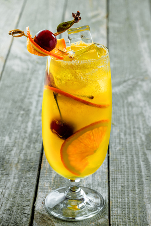 Alcoholic punch cocktail in a long glass. Delicious drink made of alcohol, fruit juice, orange and cherry on a table. Close-up vertical shot.の写真素材