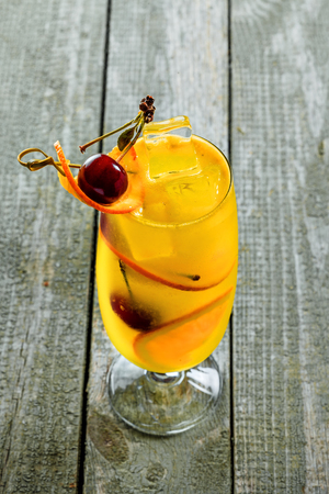 Alcoholic punch cocktail in a long glass. Delicious drink made of alcohol, fruit juice, orange and cherry on a table. Top view shot.の写真素材