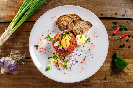 Plate with delicious tartare, toasted bread and salad on a wooden table. Healthy gourmet French food...