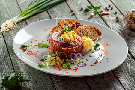 Delicious tartare with toasted bread and salad on a plate. Healthy lunch meal made of raw meat. Classical French cuisine.の写真素材
