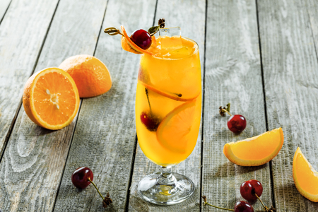 Glass of fruit cocktail drink made of fruit made of fruit juice, orange, cherry and alcohol on a wooden table. Close-up shot.の写真素材