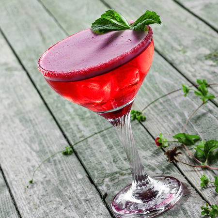 Classic frozen alcoholic cold drink with ice, raspberry, mint, martini and vodka in a glass. Cocktail with alcohol and fruit juice on a wooden table.の写真素材