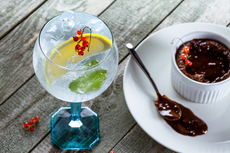 Alcoholic gin and tonic cocktail with sweet chocolate mousse on a wooden table.の写真素材