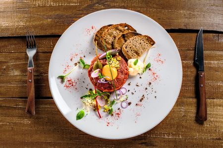 Tasty tartare with toasted bread and salad. Gourmet French meal made of raw ground meat. Delicious healthy food. Top view.の写真素材