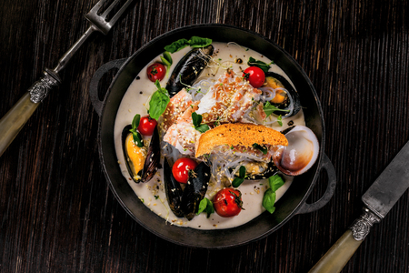 Sea bass fish fillet with mussels, crab meat and cockles with vegetables, cream sauce and rice noodles. Healthy Asian seafood meal on a table. Top view.の写真素材