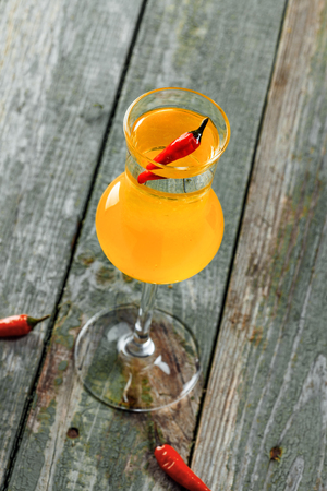 Short glass of alcoholic cocktail shot made of peach liqueur, lemon fresh and tequila on a wooden table. Top view.の写真素材