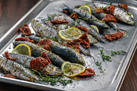 Raw sardine fish on a baking tray. Cooking of delicious seafood meal in an oven.の写真素材