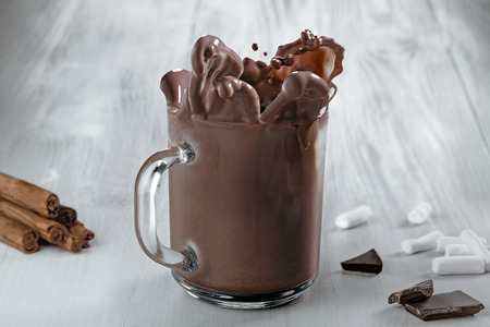 Cocoa splash in a transparent mug on a wooden table.の写真素材