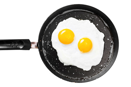 Two fried eggs in a frying pan cooked for breakfast. Delicious international meal isolated on a white background.の写真素材