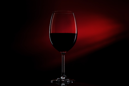 Silhouette of glass of red wine on black to red gradient background. Close-up studio shot.の写真素材