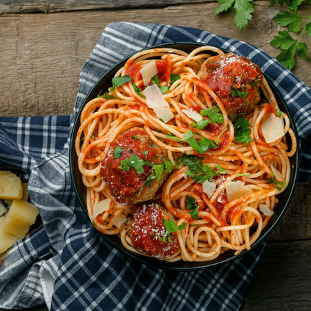 Pasta with meatballs, parmesan and tomato sauce in a clay bowl. Homemade Italian spaghetti on a rustic wooden table. Top view shot.の写真素材
