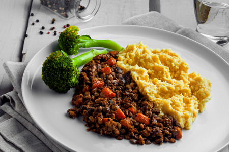 Shepherdâs pie made of smashed potatoes, minced meat, lentil and vegetables on a white wooden table. Classic meat pie.の写真素材