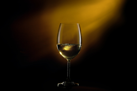 Conceptual shot of glass with white glass on a dark gradient black to yellow background.の写真素材