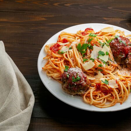 Pasta with meatballs, parmesan and tomato sauce on a plate.  Homemade Italian spaghetti on a rustic wooden table.の写真素材