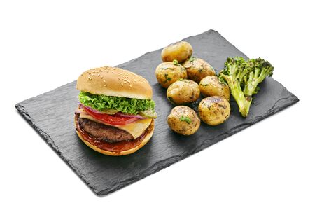 Hamburger with grilled vegetables and scallion served on a stone black board isolated on white background.の写真素材