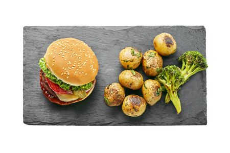 Classic hamburger with tomato, lettuce and onion served with grilled potatoes and broccoli isolated on white background. Top view, directly above.の写真素材