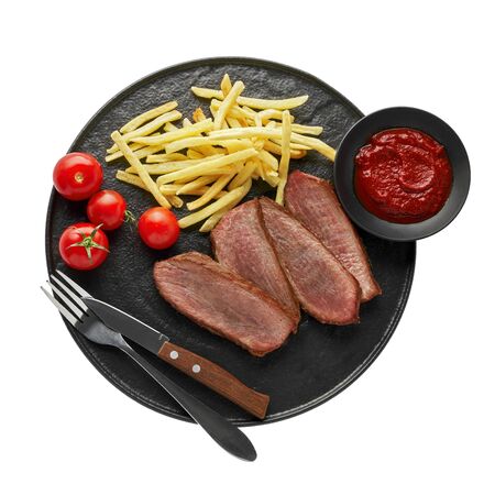 Gourmet medium rare beefsteak with French fries and fresh cherry tomatoes on a black plate with fork and knife isolated on white background. Top view, directly above shot.の写真素材