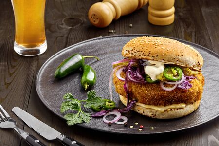 Sandwich made of chicken burger red onion, pickled cucumber, jalapeno and mayonnaise with glass of beer. Top view, directly above shot.の写真素材