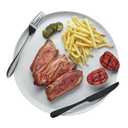 Delicious medium rare steak with French fries, pickled cucumber and grilled cherry tomatoes on a plate. Classic meat meal isolated on white background. Top view, directly above.の写真素材