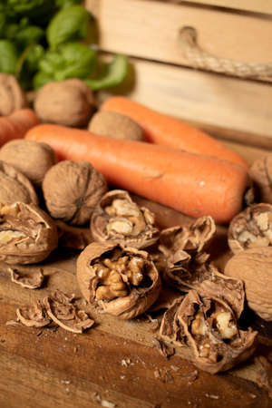 Carrots and walnuts on wooden table, with basil in the background. Fresh fruit and vegetables, with wooden box.の写真素材