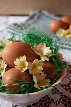 Easter table, simple eggs with primrose and grass. White lace tablecloth, and white bowl.の写真素材