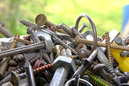 Photo shows mixture of various screws with green background.の写真素材