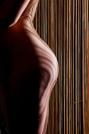 Photo shows a woman lighted and shadowed on the black background.の写真素材
