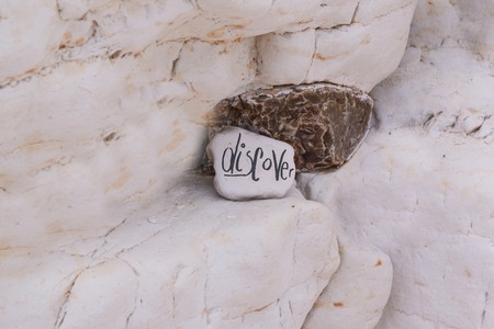 Photo shows close-up view of colourful beach stone with sign.の写真素材