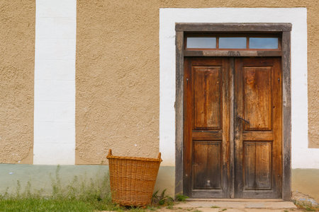 This photo shows a closeup of old wooden doors with basket in the village.の写真素材