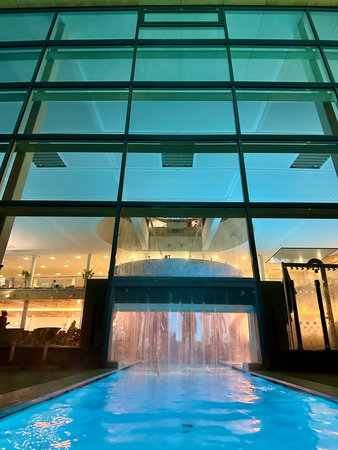 Swimming pool in modern office building at night with reflections on glass