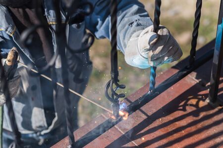 A worker welding metal handrails on the stairs. Ukraine.の写真素材