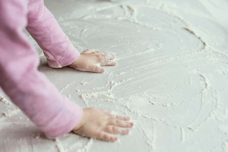 The little girl is playing in the kitchen, hands in flour. Funの写真素材