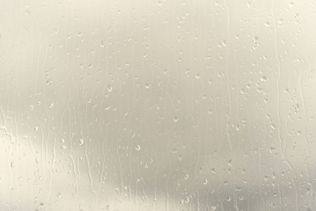 Raindrops on glass, spectacular sky background with color effectの写真素材