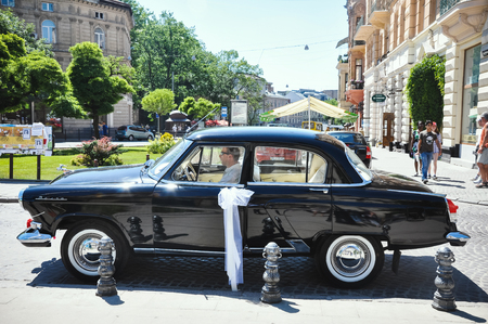 Lviv, Ukraine - June 5, 2011: Soviet car 60-xx years Volga GAZ-21. The driver expects young couple is crowned in the church.のeditorial素材