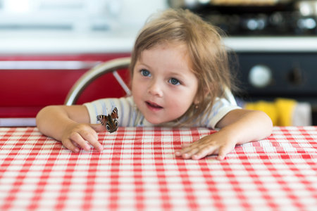 Little girl holds on the hand the Aglais io butterfly and watches for him, emotionsの写真素材