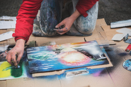 Lviv, Ukraine - January 21, 2018: Spray paint show, young beautiful sitting on the knees and drawing...