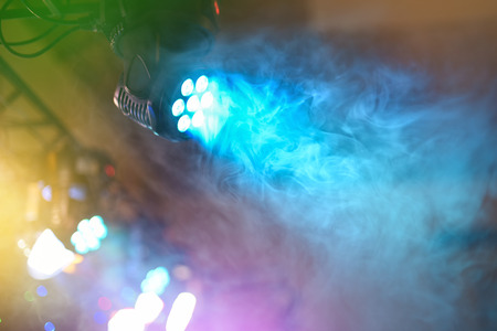 The color LED spotlight shines through dispersing smoke, entertainment equipment, light music at dance party, copyspaceの写真素材