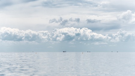 Seascape - cloudy sky above a quiet sea, buoys and ships in the distanceの写真素材