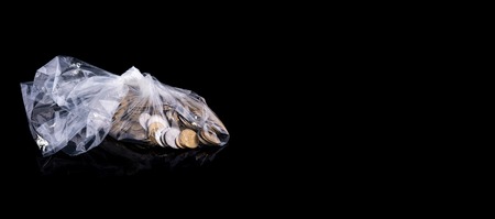 Group of coins in a polyethylene package isolated on black background with reflection, idea - savings. Ukrainian moneyの写真素材