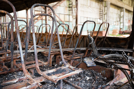 Consequences of a fire in the bus, accident. Scorched passenger seats, damaged floor, blackness around, inside busの写真素材